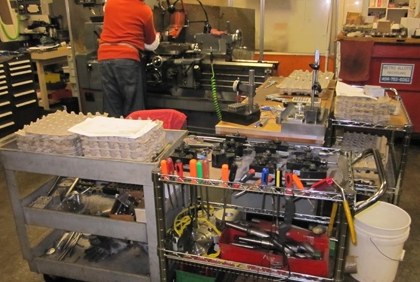 Machinist at work behind carts of tools and parts